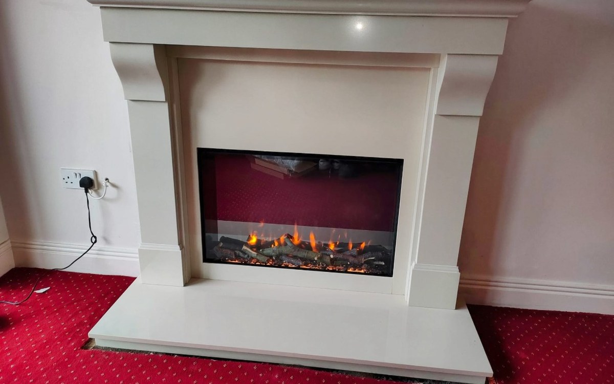 An electric fire fitted into a cream fireplace surround by Stove Fit
